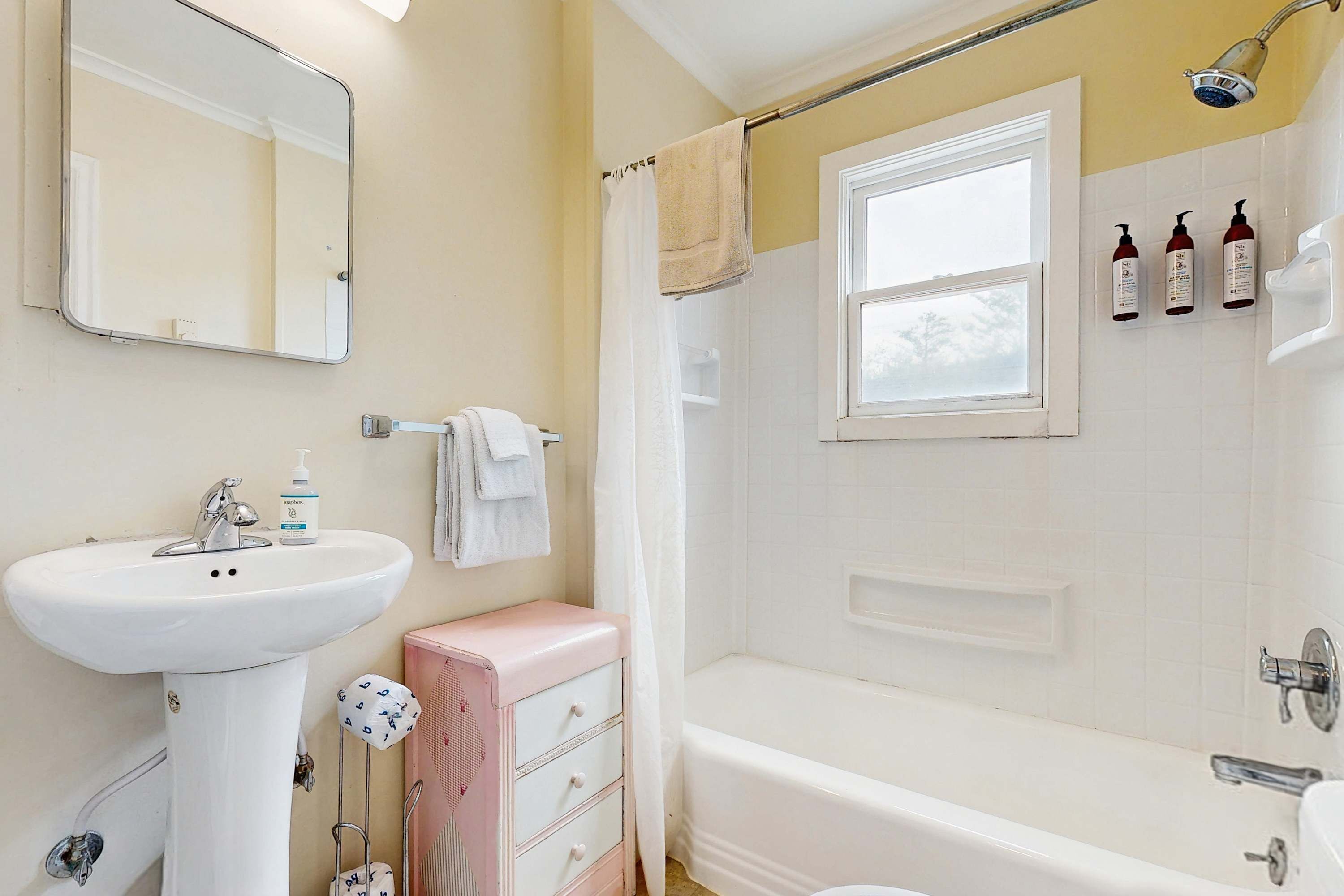 A bathroom with a sink, mirror, vanity, and bathtub.