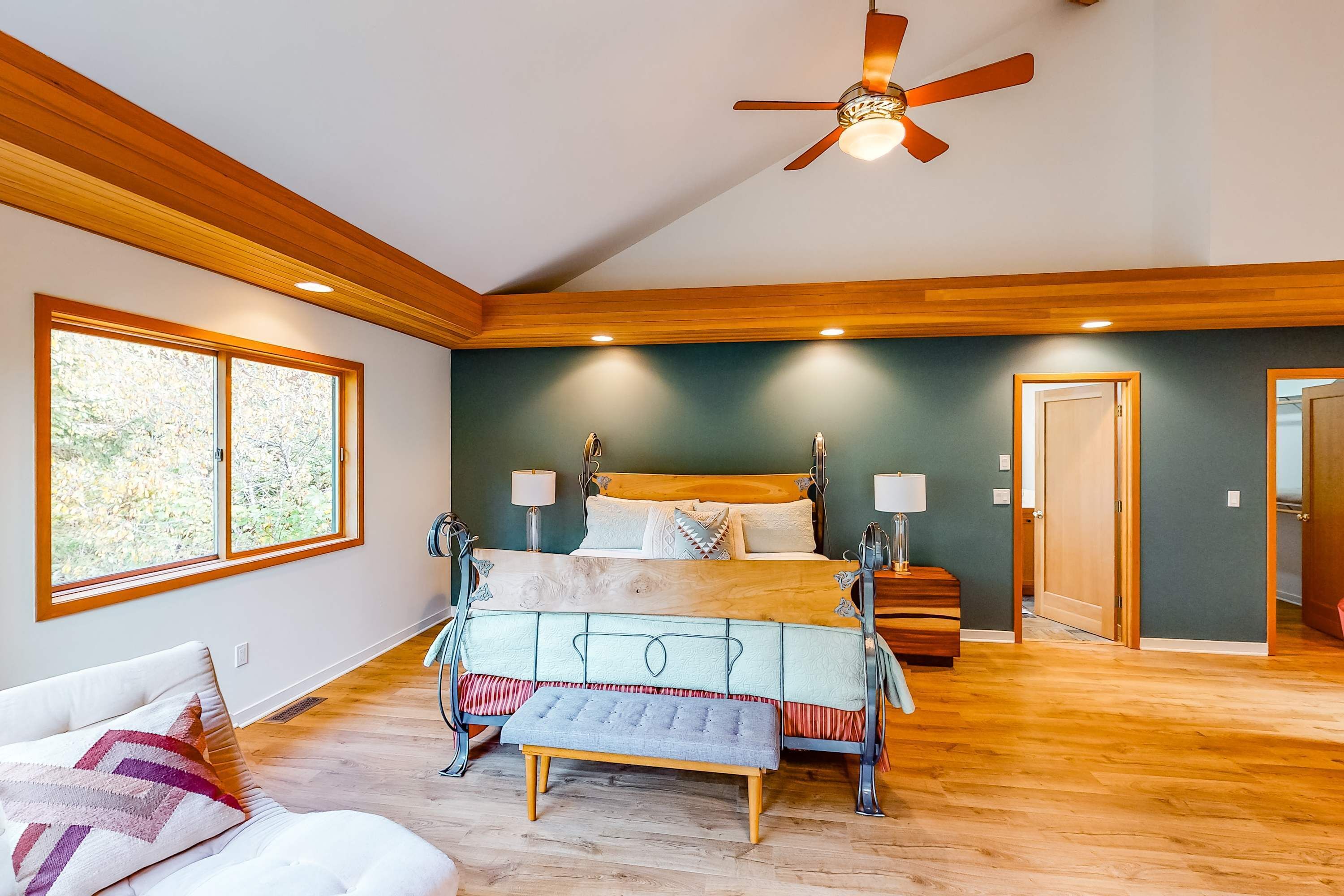 Une chambre avec un grand lit, un plafond en bois et une vue sur l’extérieur par une fenêtre.