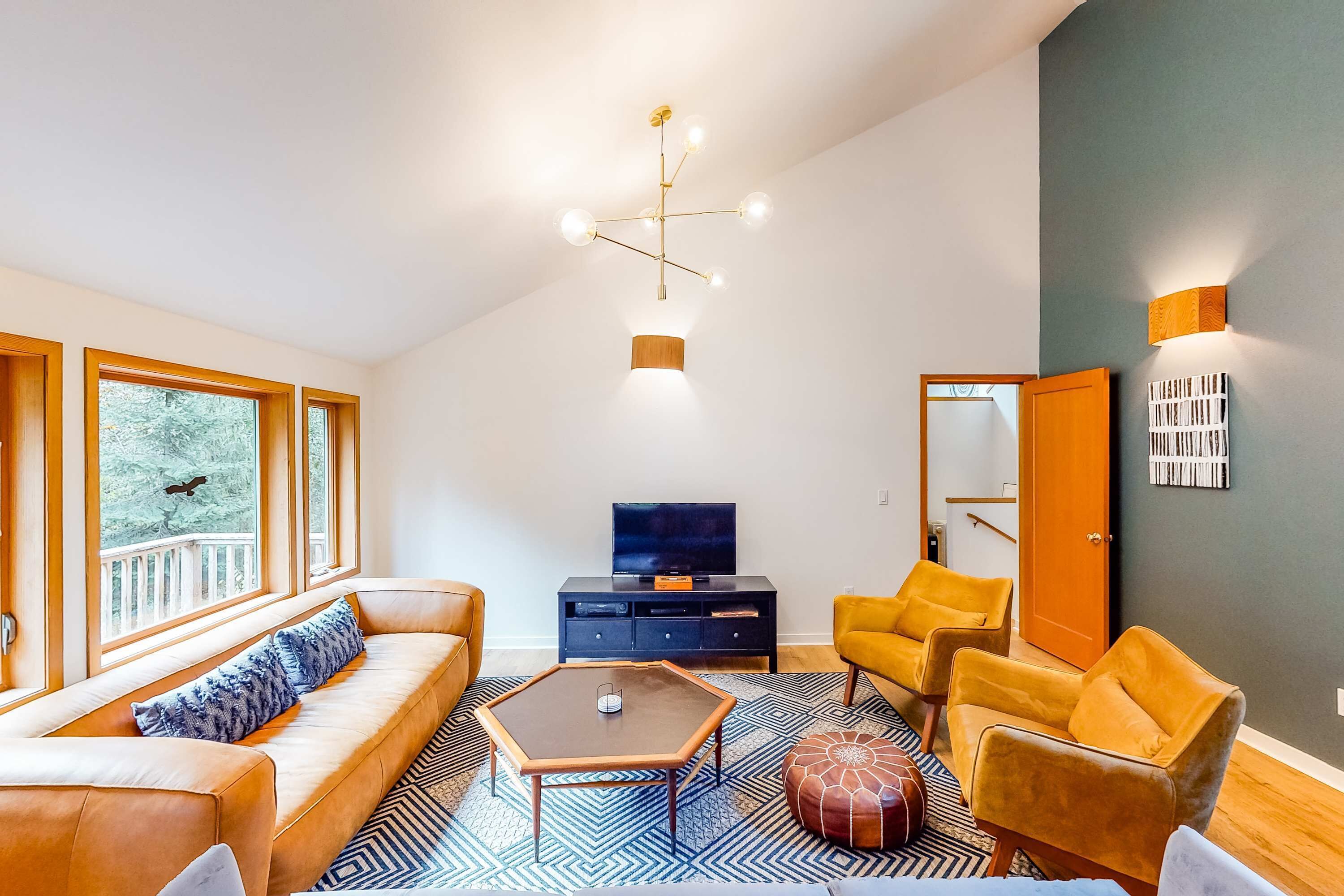 A modern living room with a sofa, armchairs, a coffee table, and a TV.