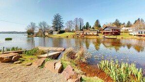 Une propriété au bord du lac, dotée d’un quai en bois, d’un étang parsemé de nénuphars et de maisons aux grandes fenêtres.
