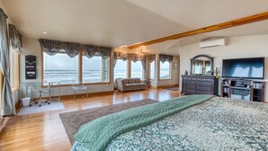 A spacious bedroom with a large bed, a TV, a sofa, and a desk.