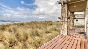 A coastal property with a wooden deck leading to a stone-covered porch overlooking the ocean.