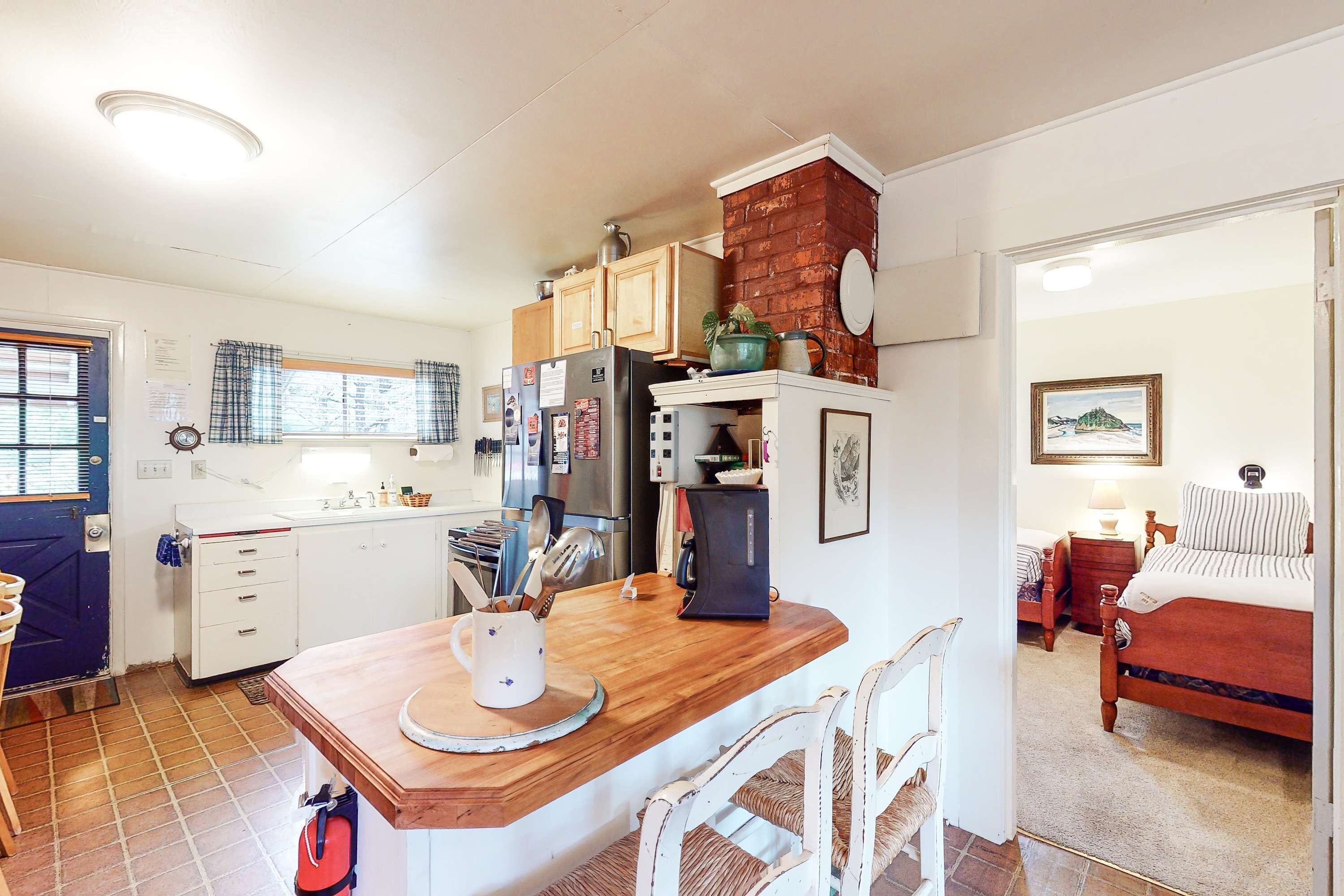 Une cuisine de taille réduite avec un plan de travail en bois, des placards blancs et un mur décoratif en briques.