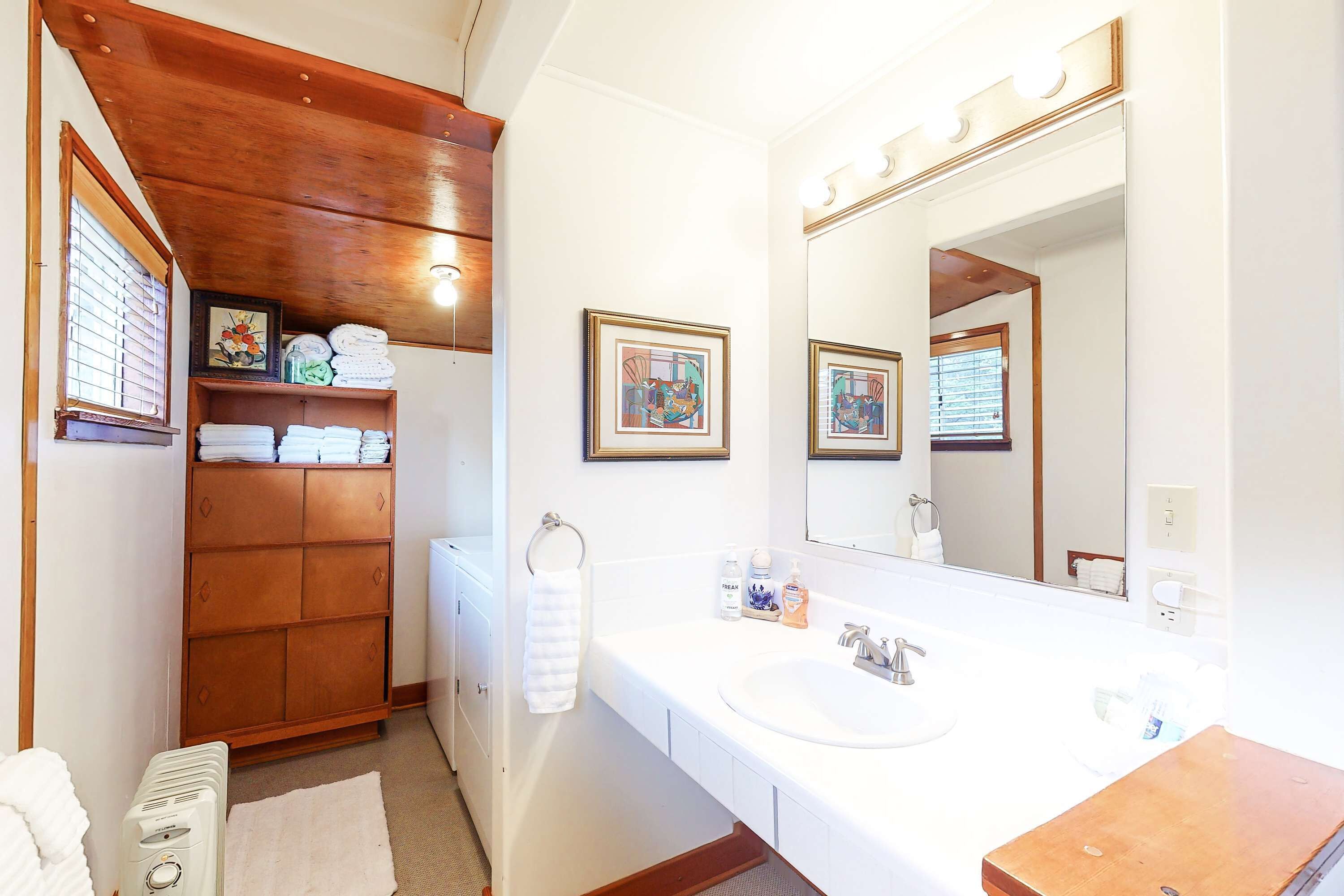 Une salle de bain avec un meuble-lavabo en bois, un grand miroir et un lavabo blanc.