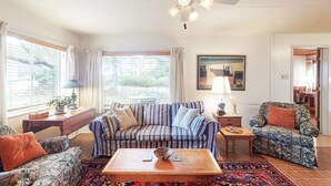 A living room with a striped sofa, patterned armchairs, a coffee table, and a ceiling fan. - Dog-Friendly Beach Cottage in Peaceful Neskowin (Neskowin)