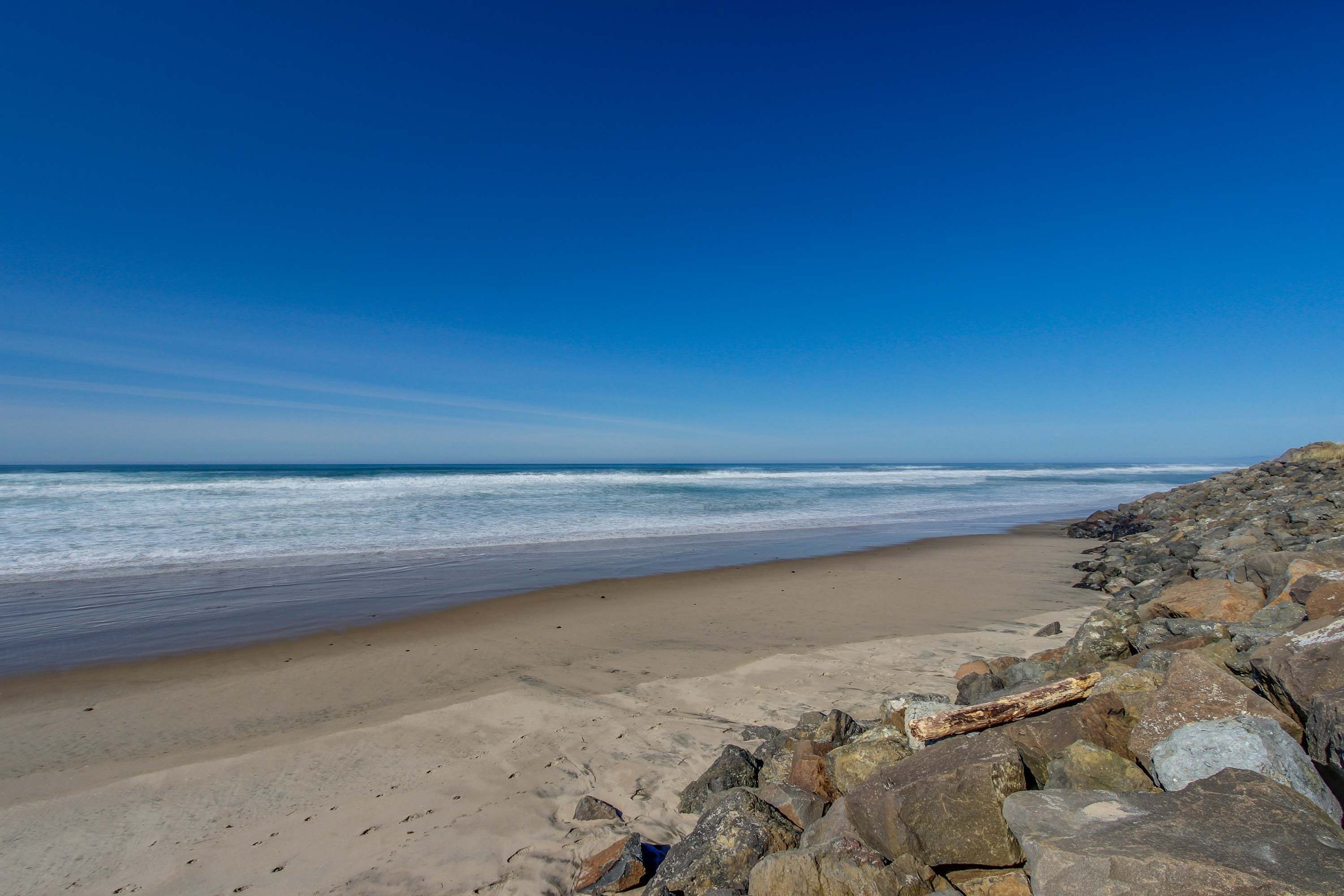 A beach with a rocky shoreline and waves in the background.