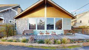 Une maison avec une façade en pierre, une terrasse en bois et une grande fenêtre.
