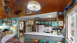Une cuisine chaleureuse avec un îlot central, des tabourets de bar en bois et un lustre.