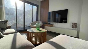 A modern living room with a large window, a flat-screen TV, and a comfortable seating area. - 3bd with a private heated pool in Sholan 2 ElGouna (Second Hurghada)