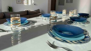 A dining table set with blue plates and glasses, a brown sofa, and framed artwork on the wall. - 3bd with a private heated pool in Sholan 2 ElGouna (Second Hurghada)