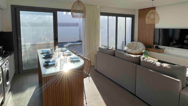 A modern kitchen with a central island, a dining area with chairs, a sofa, and a large TV. - 3bd with a private heated pool in Sholan 2 ElGouna (Second Hurghada)