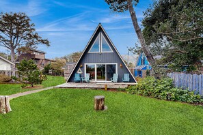 Et moderne A-formet hus med terrasse og udendørs siddeområde.