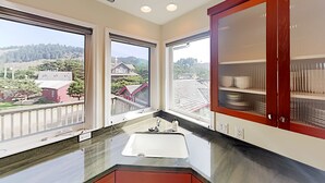 Eine Küche mit einem großen Fenster, einer Spüle und einem Schrank mit Glastüren.