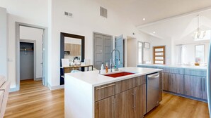 Una cocina moderna con armarios de madera, una isla central y un lavavajillas integrado.