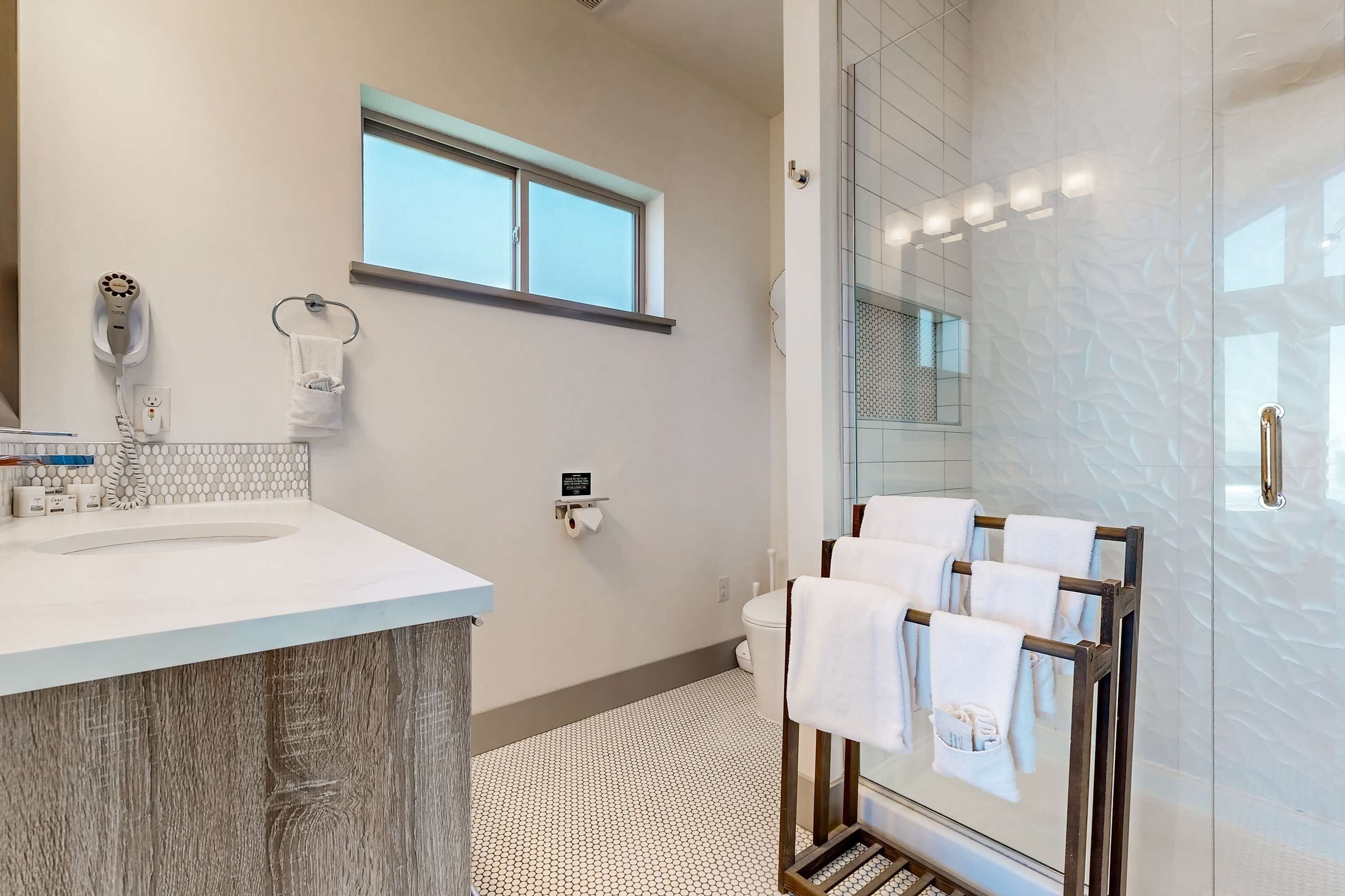 Een moderne badkamer met een grote wastafel, een handdoekhouder, een toilet en een douchecabine met glazen wanden.