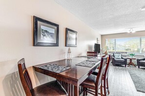 A dining area with a wooden table, chairs, and framed pictures on the wall. - Oceanfront 2nd floor condo with river ocean views balcony (Neskowin)