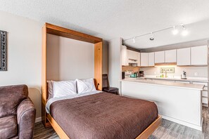 A compact room with a bed, a chair, a kitchenette, and a small dining area. - Oceanfront 2nd floor condo with river ocean views balcony (Neskowin)