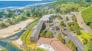 An aerial view of a coastal town with a large building complex, a beach, and a road.