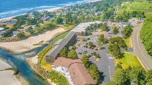 Vista aérea de un pueblo costero con un gran complejo de edificios, una playa y un estacionamiento.