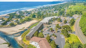 An aerial view of a coastal town with a large building complex, a beach, and a parking lot.