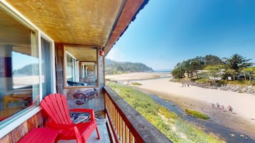A balcony with red chairs and a view of a beach.