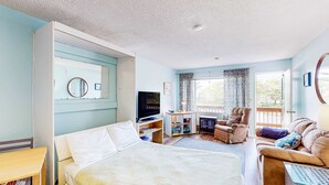 Une chambre à coucher avec un lit, une télévision, un bureau, une chaise et un canapé.