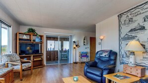 Ein Wohnzimmer mit Holzboden, einem Ledersofa, einem Couchtisch aus Holz und einem Fernseher auf einem Holzständer.