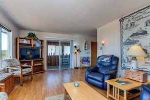 Ein Wohnzimmer mit Holzboden, einem Ledersofa, einem Couchtisch aus Holz und einem Fernseher auf einem Holzständer.