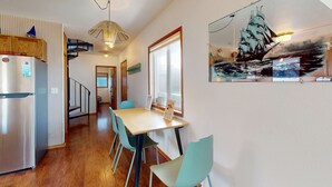 Eine moderne Küche mit Kühlschrank, Holzschränken und einem Essbereich mit Tisch und Stühlen.