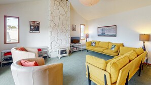 Ein Wohnzimmer mit einer Steinwand, einem Fernseher, gelben Sofas und einem weißen Sofa.
