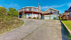 A two-story house with a balcony, a garage, and a driveway. - Spacious Dog Friendly Getaway with Boat Parking Perfect for Two Families (Pacific City)