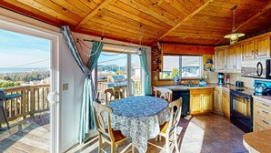 A wooden cabin with a kitchen and dining area, featuring a large window and a deck. - Spacious Dog Friendly Getaway with Boat Parking Perfect for Two Families (Pacific City)