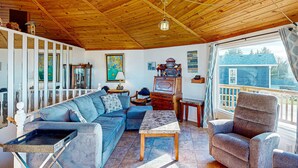 A cozy living room with a wooden ceiling, a sofa, a recliner, a coffee table, and a window with a view of the outside. - Spacious Dog Friendly Getaway with Boat Parking Perfect for Two Families (Pacific City)