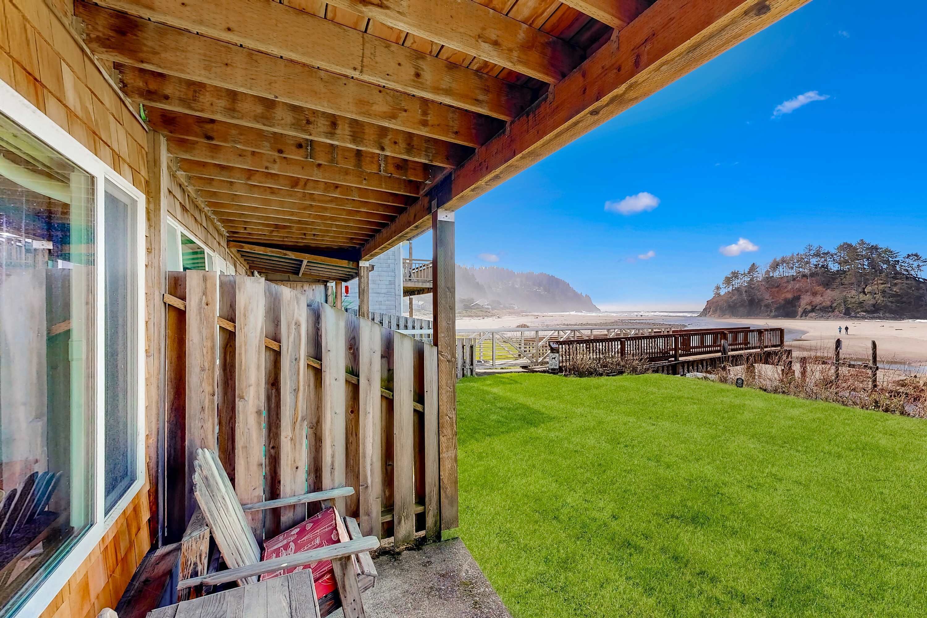 Un bâtiment en bois doté d’un balcon donnant sur une plage et une zone herbeuse.