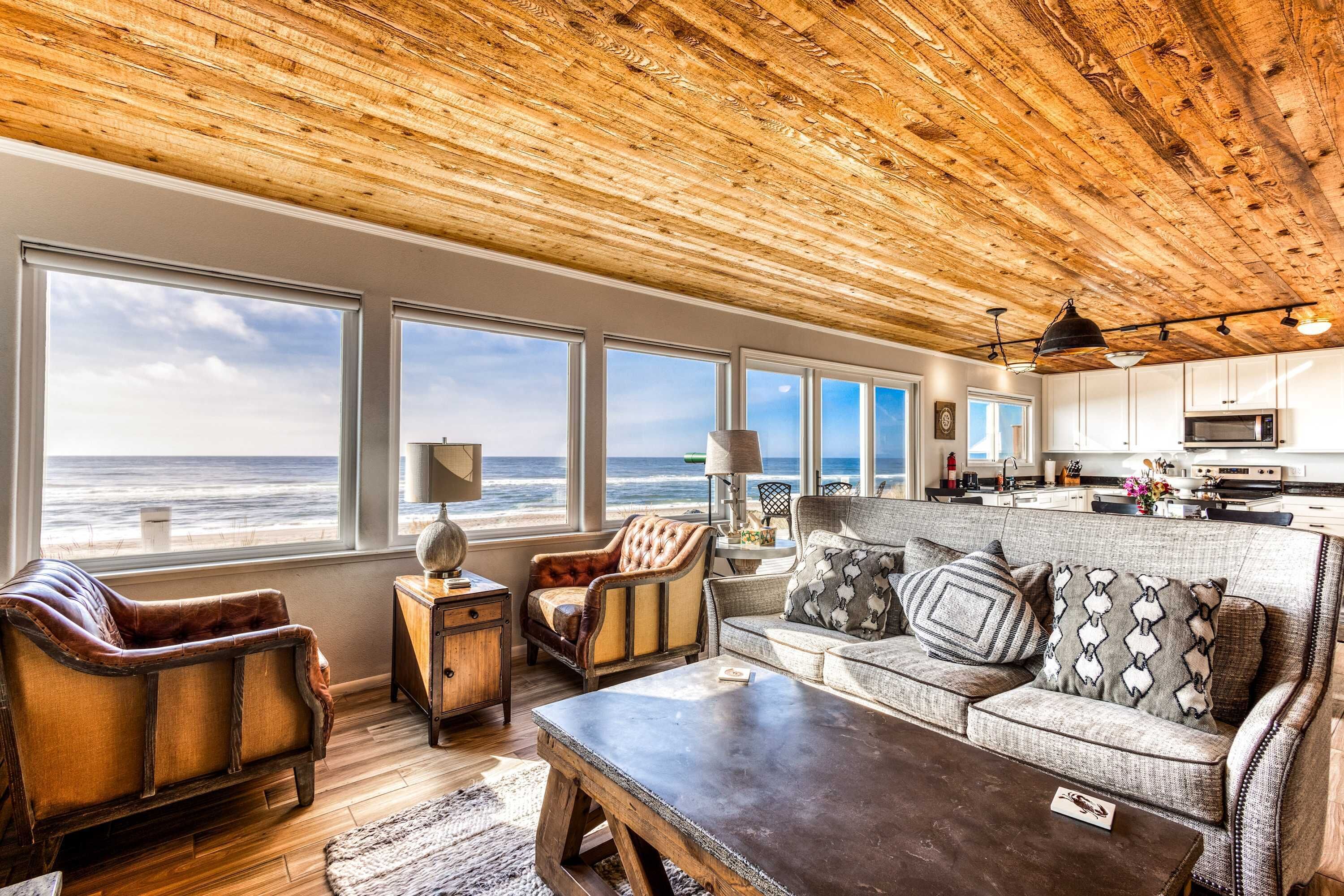 A coastal living room with a view of the ocean, wooden ceiling, and modern furniture.