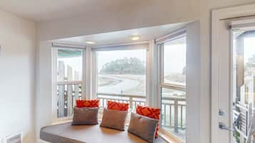 A bay window with three wicker baskets and orange cushions.