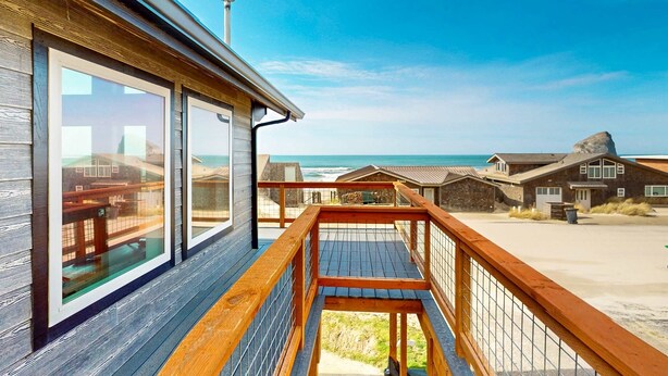 Une terrasse en bois offrant une vue sur la plage et l’océan.