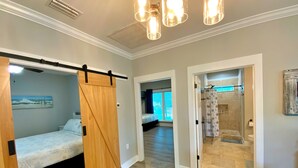 Ein geräumiges Zimmer mit einem großen Bett, einer Holztür zum Schieben und einem Duschbereich.