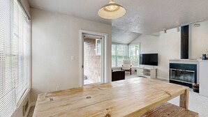 Ein großzügiger Wohnbereich mit Esstisch aus Holz, Kamin und Fernseher.