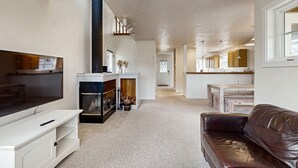 Ein modernes Wohnzimmer mit Kamin, Fernseher und Ledersofa.