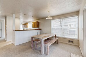 A kitchen with a wooden table and bench, white cabinets, and a window with blinds. - Modern two story dog friendly home located close to beaches and trails (Pacific City)