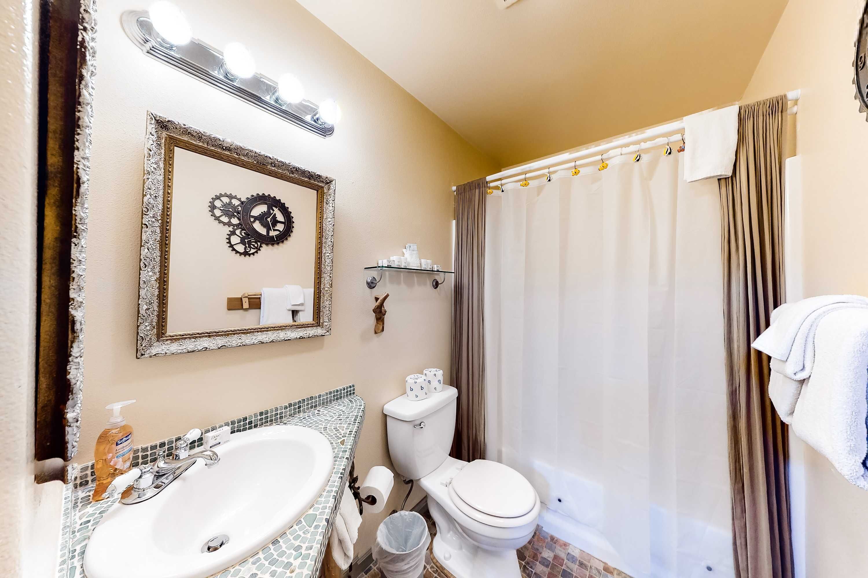 A bathroom with a sink, toilet, and shower curtain.