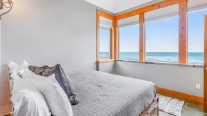 Ein Schlafzimmer mit einem Bett, einem Nachttisch und einem Fenster mit Meerblick.