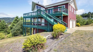 Una casa de dos pisos con una escalera verde y un balcón.