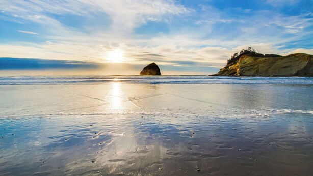 Uma praia com uma grande formação rochosa e um penhasco.