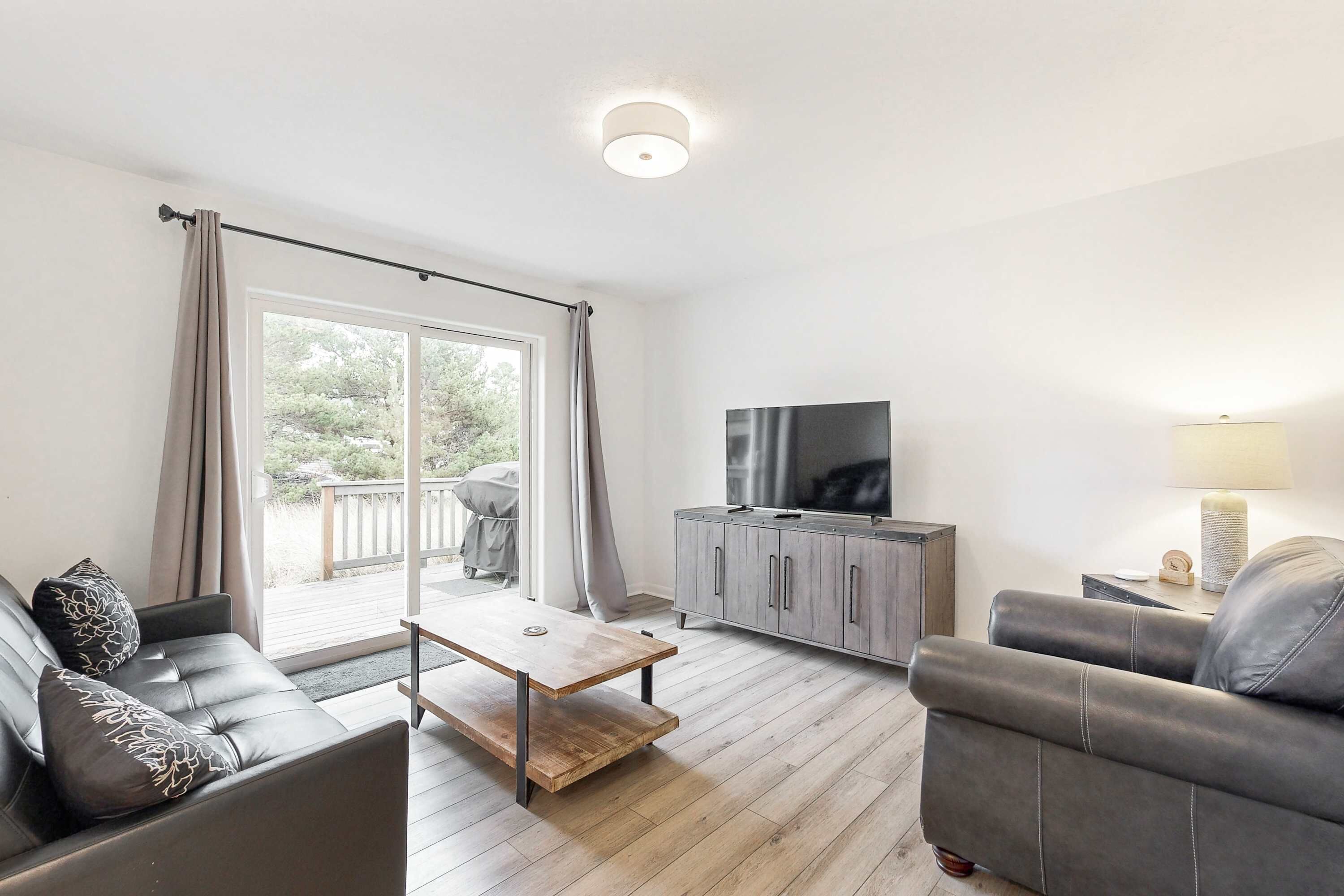 Un salon moderne comprenant un canapé, une table basse, un téléviseur et un meuble.