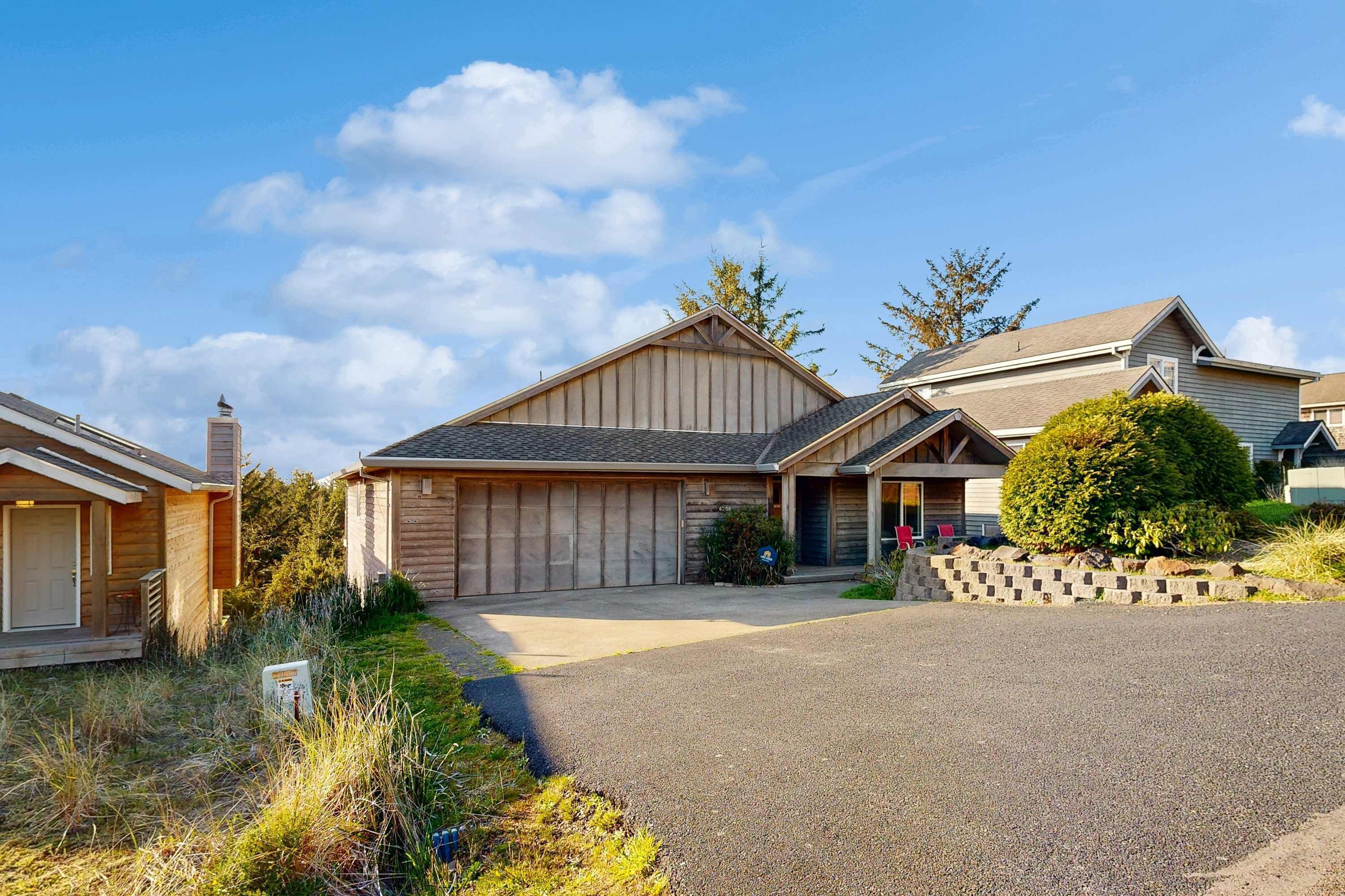 Une maison d’habitation avec un garage, une allée et une pelouse bien entretenue.