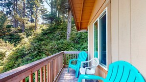 Une terrasse en bois avec deux fauteuils Adirondack turquoise et une rambarde en bois.