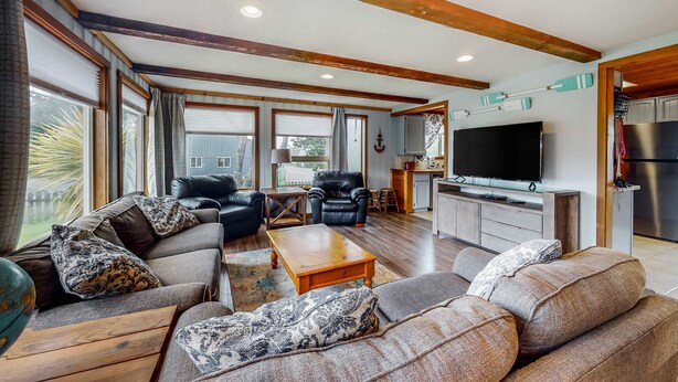 Ein großzügiges Wohnzimmer mit einer großen Sofagarnitur, einem Holztisch und einem Flachbildfernseher.