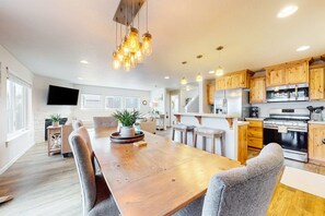 Una cocina moderna con armarios de madera, electrodomésticos de acero inoxidable y una amplia mesa de comedor.
